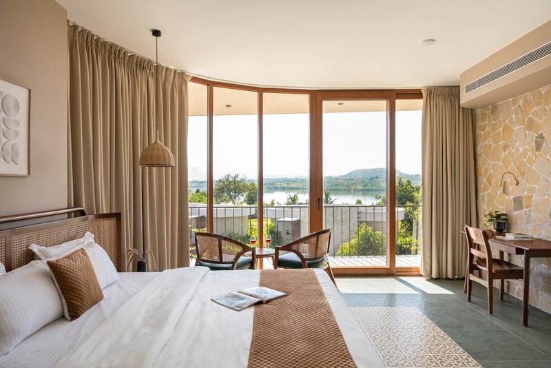 Bedroom with curved glazed doors opening to a planted terrace with lake views beyond