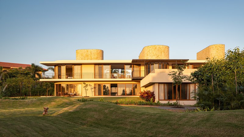 Garden facade with three cylindrical cork-clad towers and horizontal bands of glazing at sunset