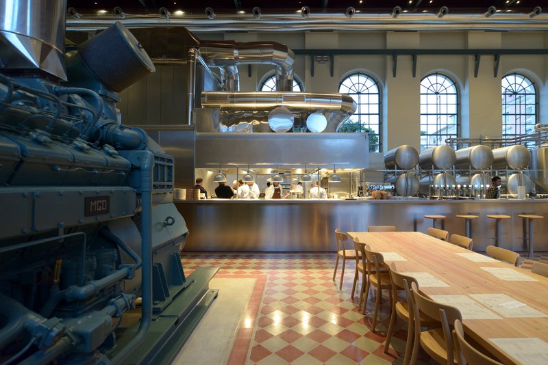 Interior view of the double-height dining space with stainless steel kitchen counter and original chequered tile floor