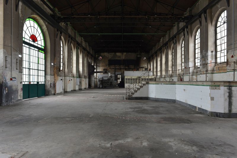 Interior view of the vacant hall with arched windows and remnant tile wainscoting before adaptive reuse