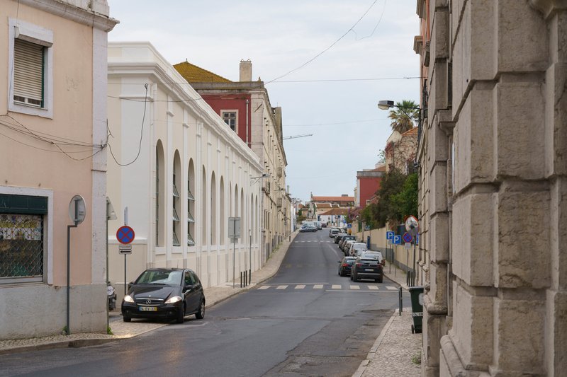 Sloping street lined with white arcaded buildings and overhead power lines crossing the sky