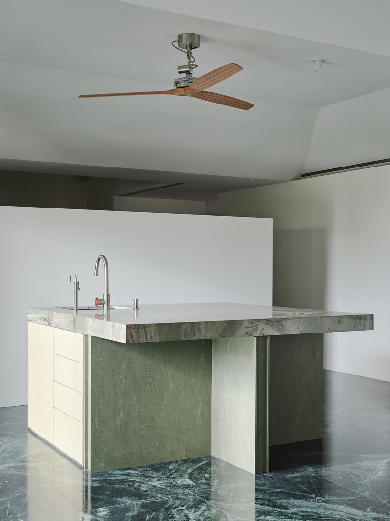 This architectural image showcases a modern kitchen island with a stone countertop and wood cabinetry, set against a marble floor. The design emphasizes clean l
