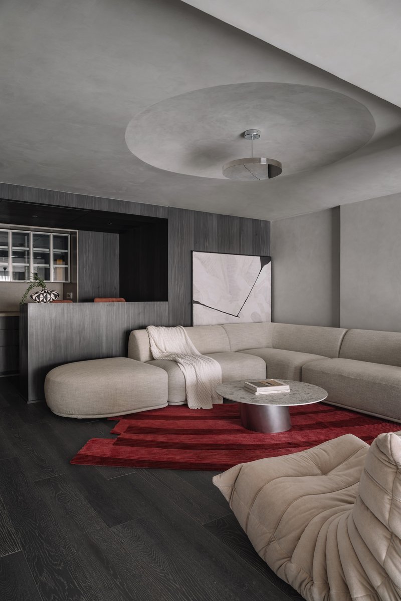 Living room with circular ceiling recess, dark timber millwork, and red geometric rug
