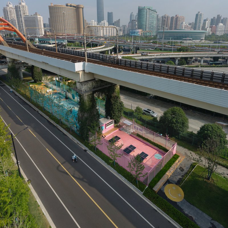 Aerial view of the pink sports court nestled between highway infrastructure and adjacent roadways