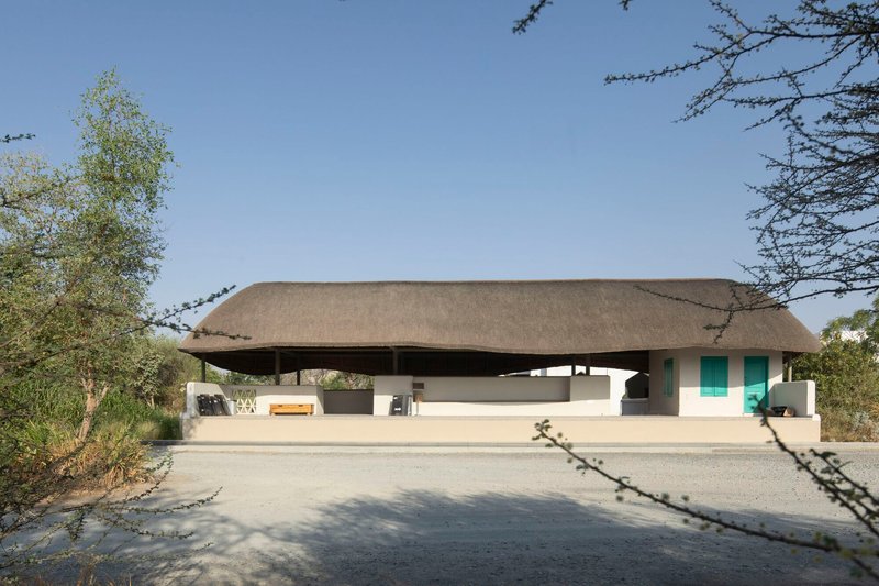 Front view of the sweeping thatched roof canopy floating above white rendered walls framed by bare trees
