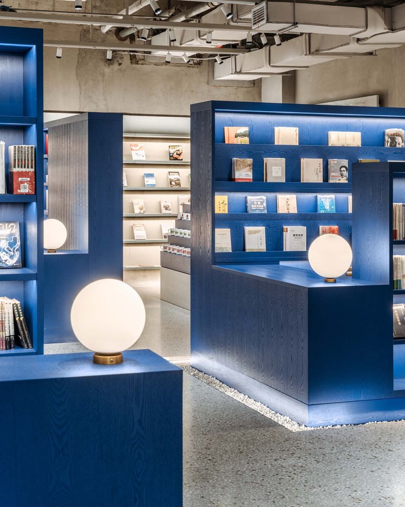 Blue stained wood shelving units with sphere lamps on brass bases and exposed ductwork above