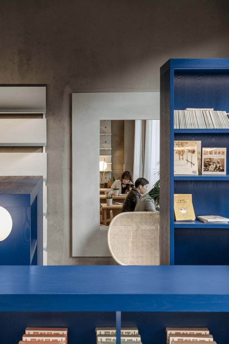 Layered view through doorways showing blue shelving, seated readers, and concrete ceiling