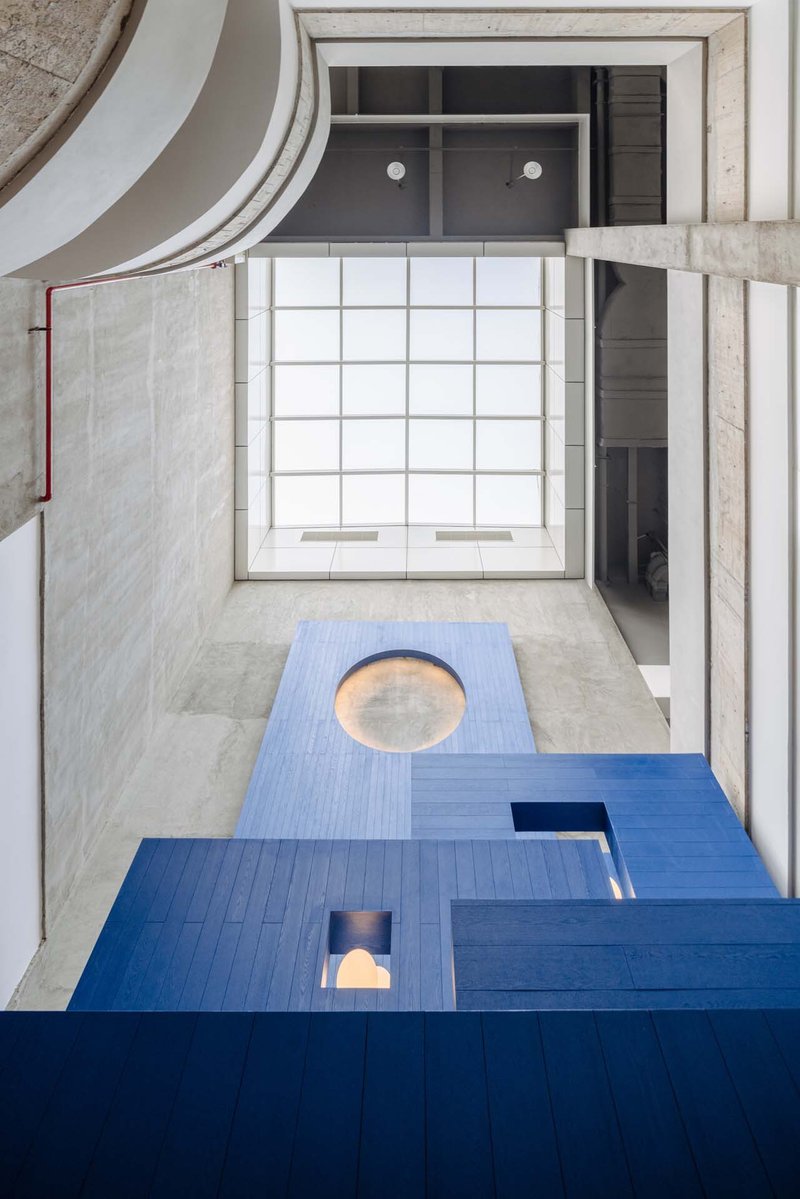 Overhead view of interlocking floor levels with circular openings and a translucent gridded skylight