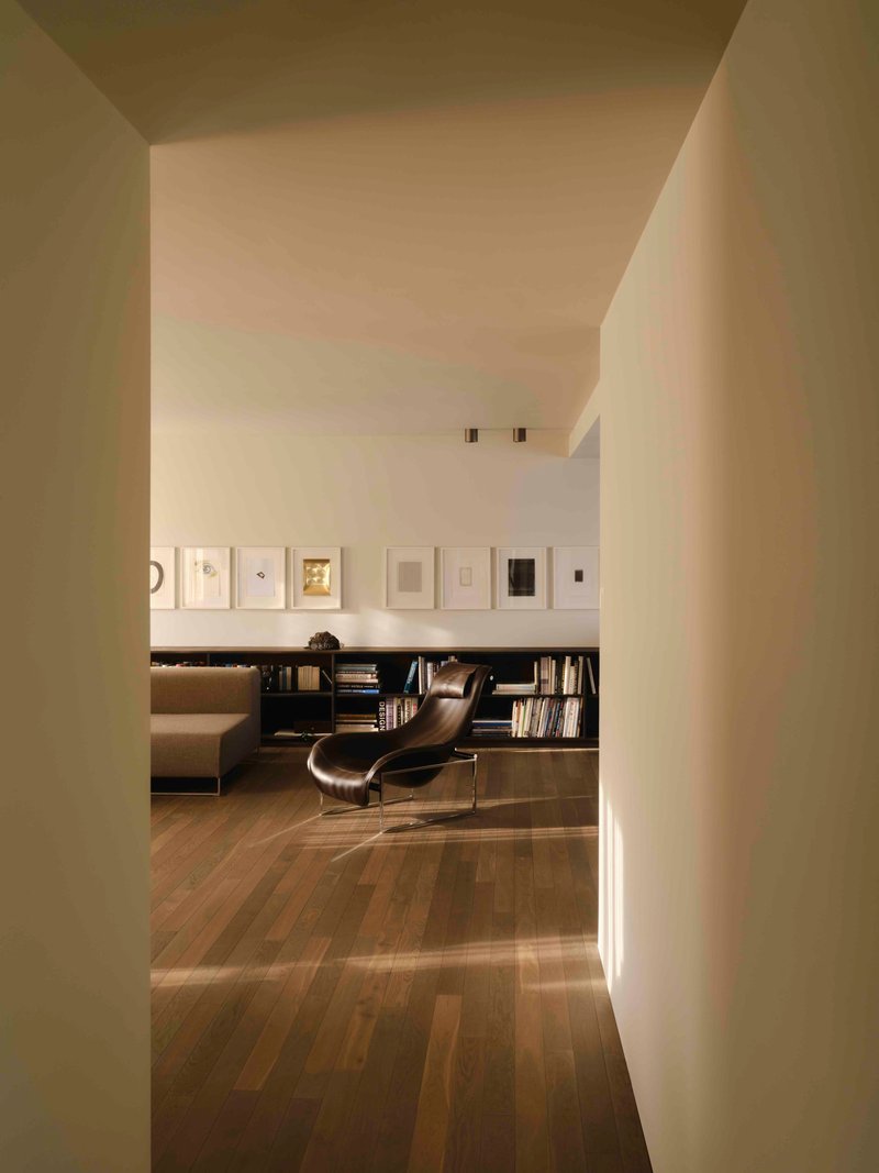 View through white plastered columns into a reading room with framed artworks and low bookshelves