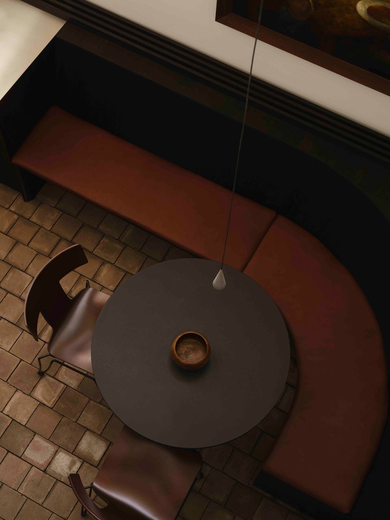 Top-down view of a round dining table with chairs over terracotta tile and cream floor zones