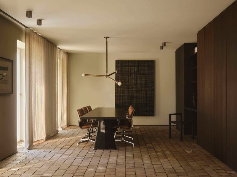 Dining room with small square tile floor and suspended brass chandelier in warm afternoon light