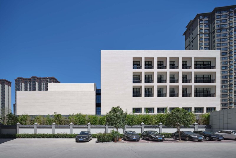 Rear elevation showing grid of square windows in white stone facade with parked cars along the street