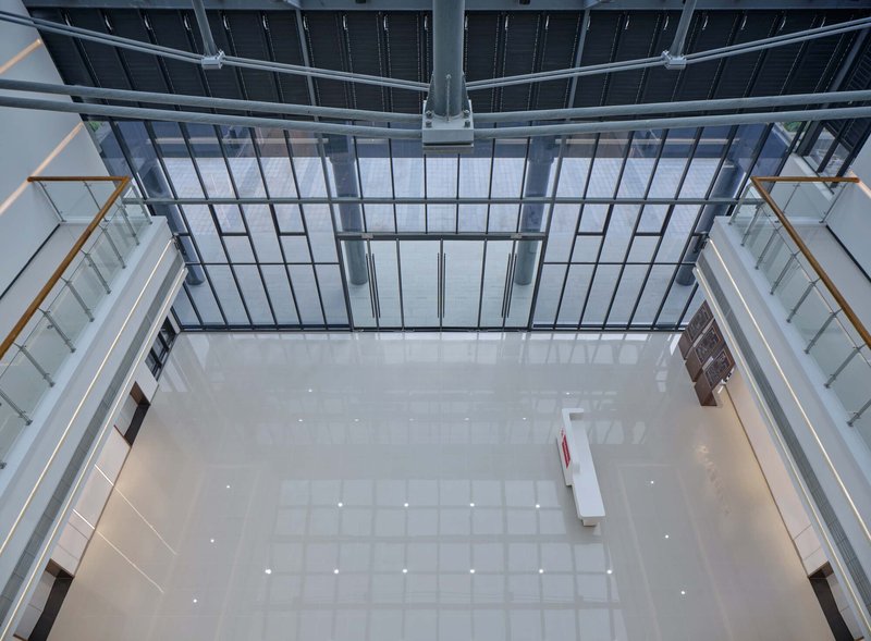 Overhead view of the central atrium with a glazed roof and white tiled floor below
