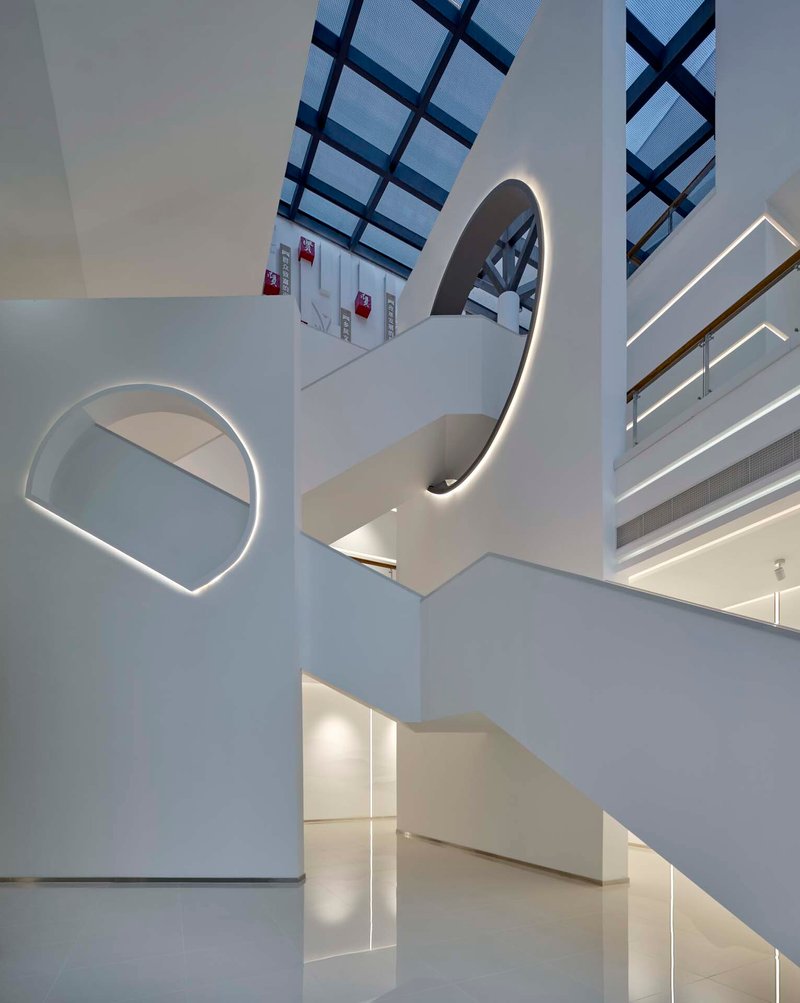 Curved white staircase with integrated LED lighting rising through the multi-level atrium