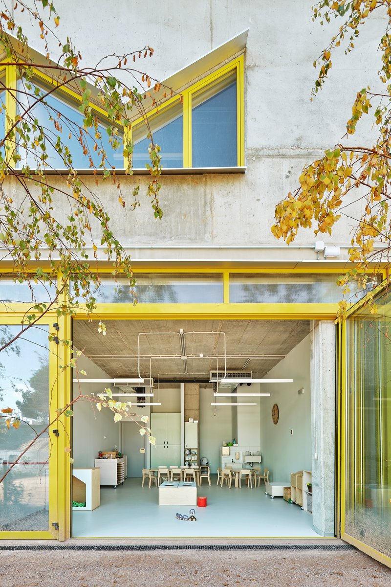 Yellow-framed sliding glass doors opening to an interior space with autumn foliage draped overhead
