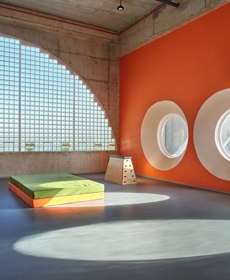 Interior room with glass block wall casting shadow on orange wall with circular porthole windows