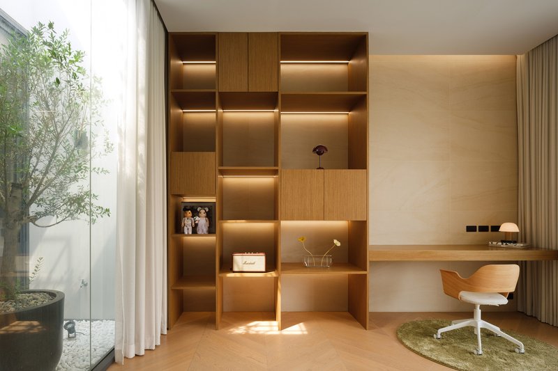 Study nook with illuminated timber shelving and view to the planted courtyard through glass