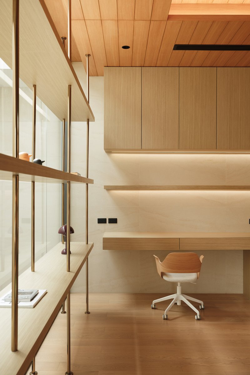 Double-height workspace with timber shelving, desk below upper storage cabinets and wood ceiling