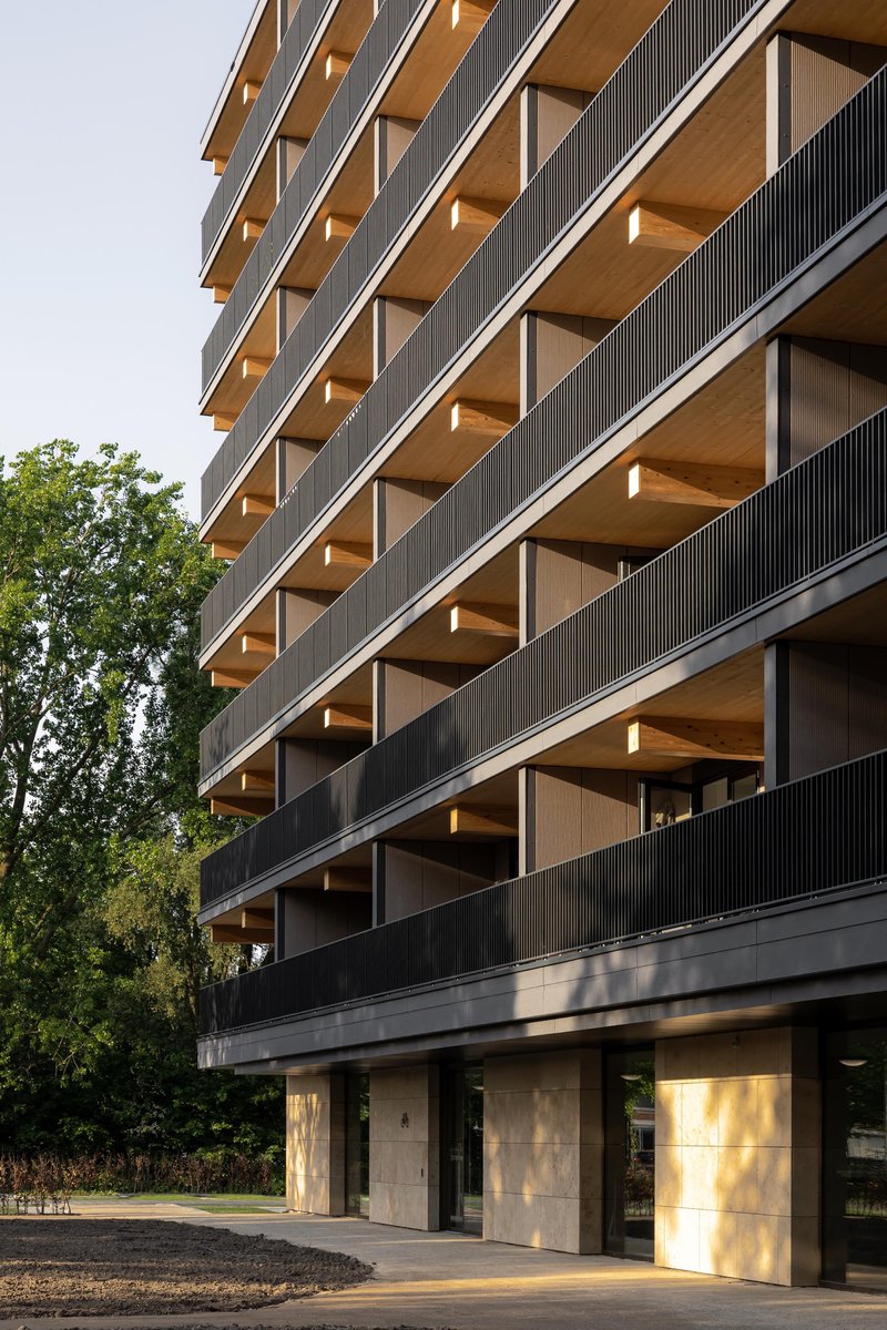 Stacked timber-lined balconies with vertical metal screening and concrete columns at ground level