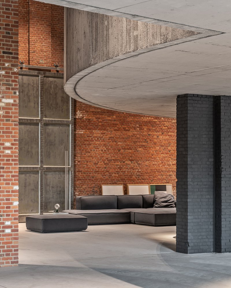 Sweeping concrete ceiling edge meeting exposed brick wall above seating area with painted brick column
