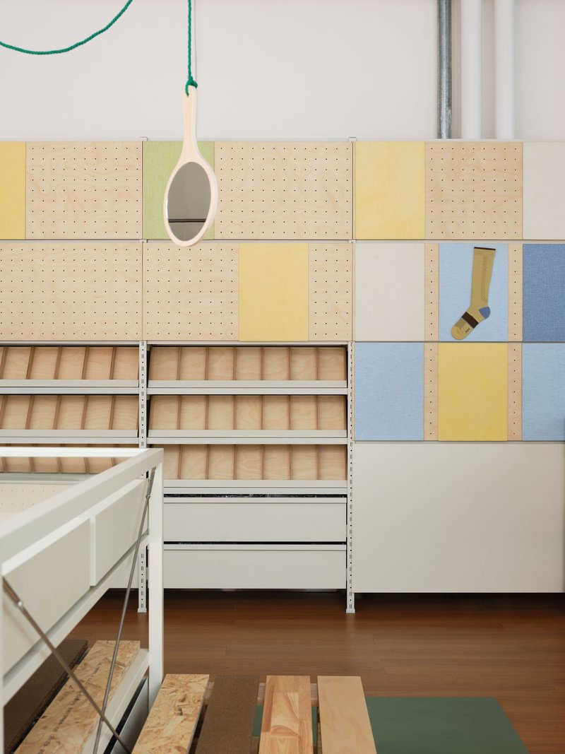 Modular pegboard wall with yellow and blue panels above timber slatted storage drawers