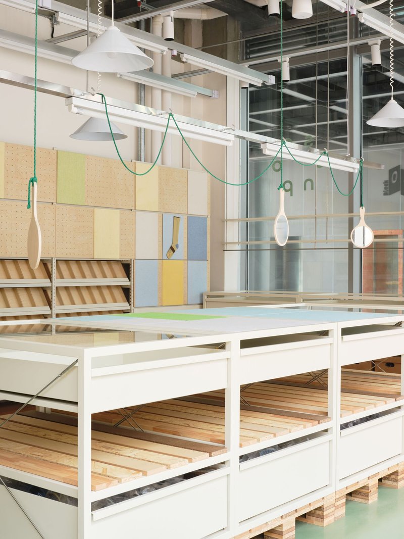 White framed display platforms beneath pendant lights suspended on green braided cords