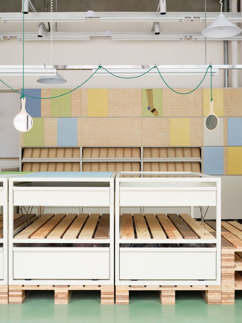 Frontal view of white powder-coated tables with slatted timber shelves on mint green rubber flooring