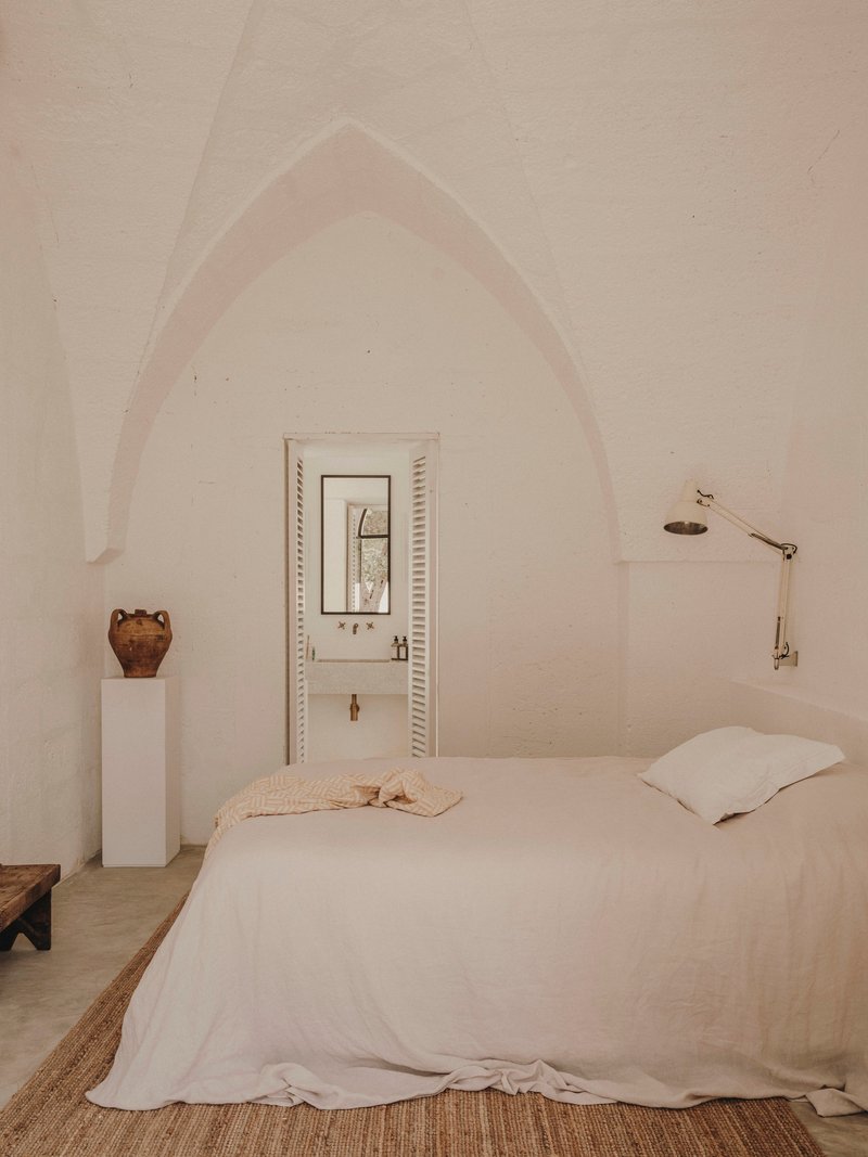 Bedroom with pointed arch vault framing doorway with louvered shutters and polished concrete floor