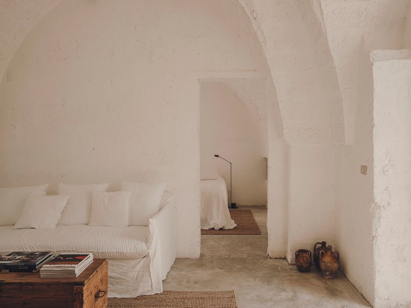 White plastered interior with vaulted arches connecting seating area to adjacent sleeping space