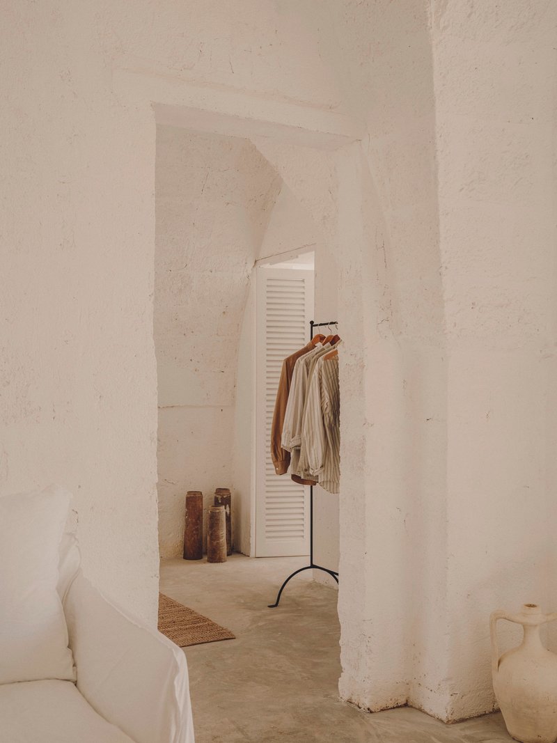 Arched passageway with freestanding clothing rack in front of louvered closet door