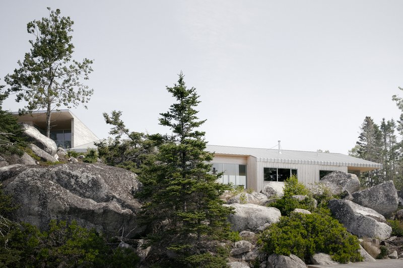 Low-slung profile with corrugated metal roof nestled among granite boulders and evergreen trees