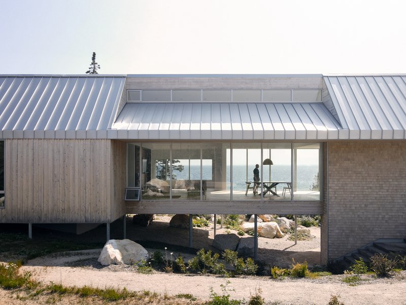 Elevated living space with glazed walls and a figure visible in afternoon light