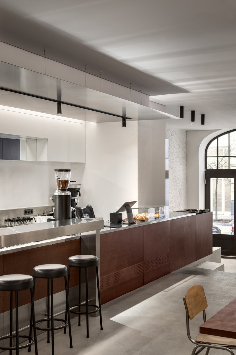 Coffee bar with dark timber base and white overhead cabinetry beneath linear suspended lighting