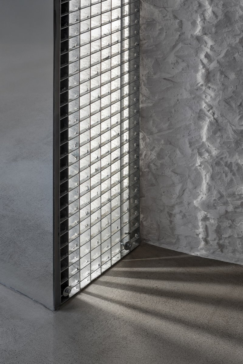 Glass block window casting diamond shadows on concrete floor beside a weathered plaster wall
