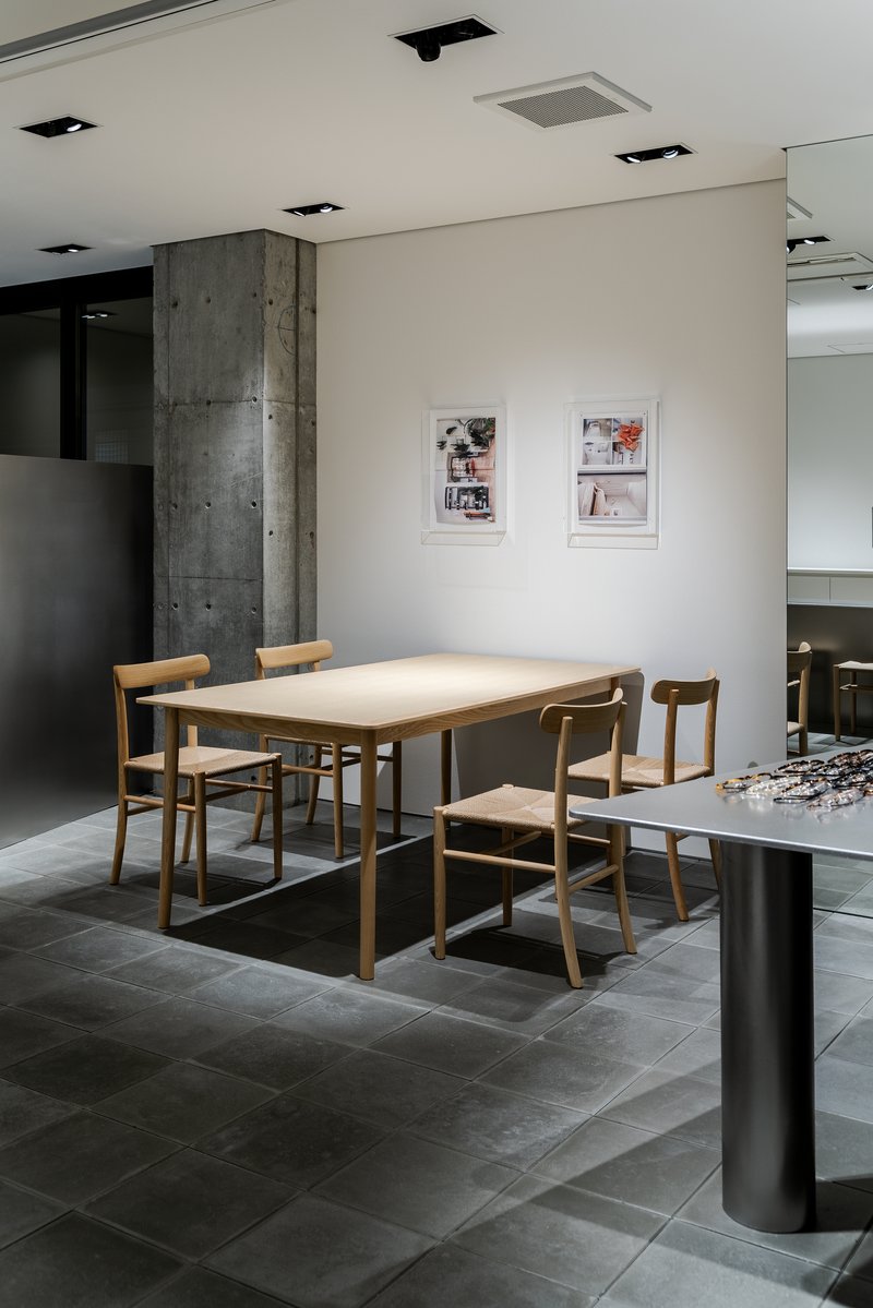 Timber dining table and chairs on grey tile floor beside an exposed concrete column