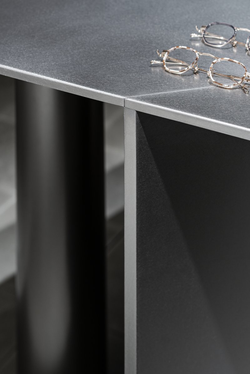 Close-up of the metal edge trim wrapping the black display counter with eyeglass frames