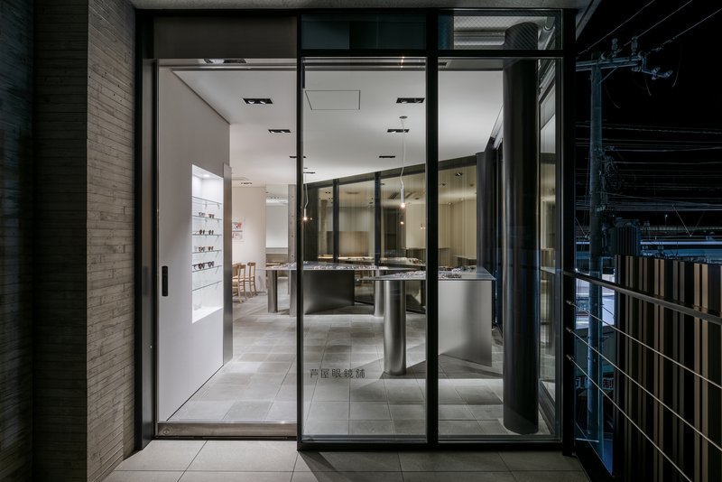 Floor-to-ceiling glass storefront entrance revealing interior display counters and pendant lights