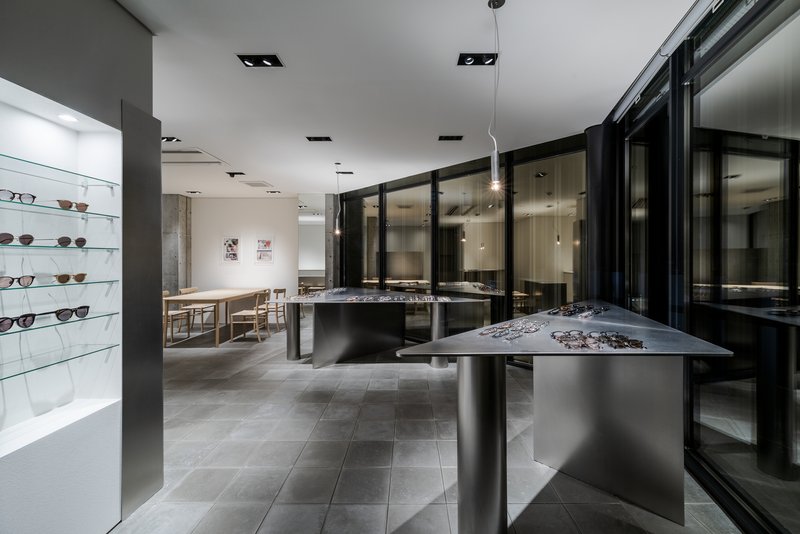 Interior of an eyewear showroom with metal display tables and black-framed glass partitions