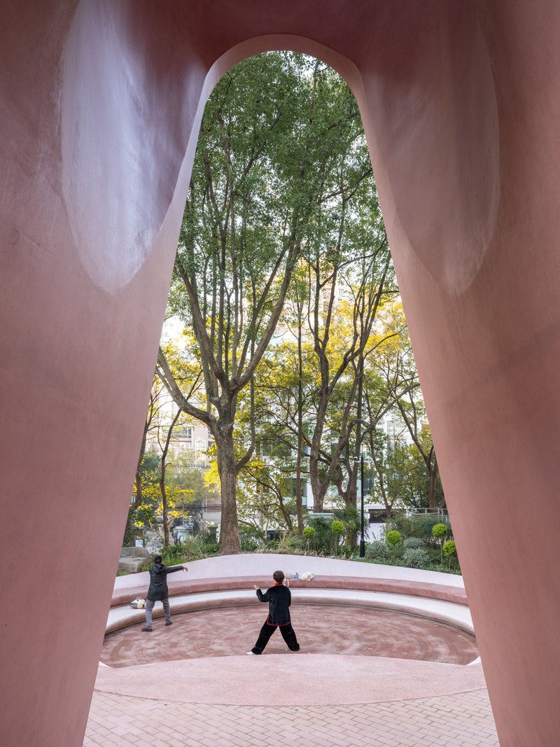 View through the tall arched opening framing a person at the amphitheater with trees beyond