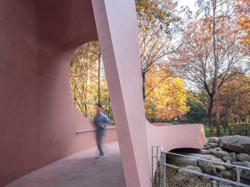 Interior walkway through the gateway with a blurred figure passing beside the curved parapet at dusk