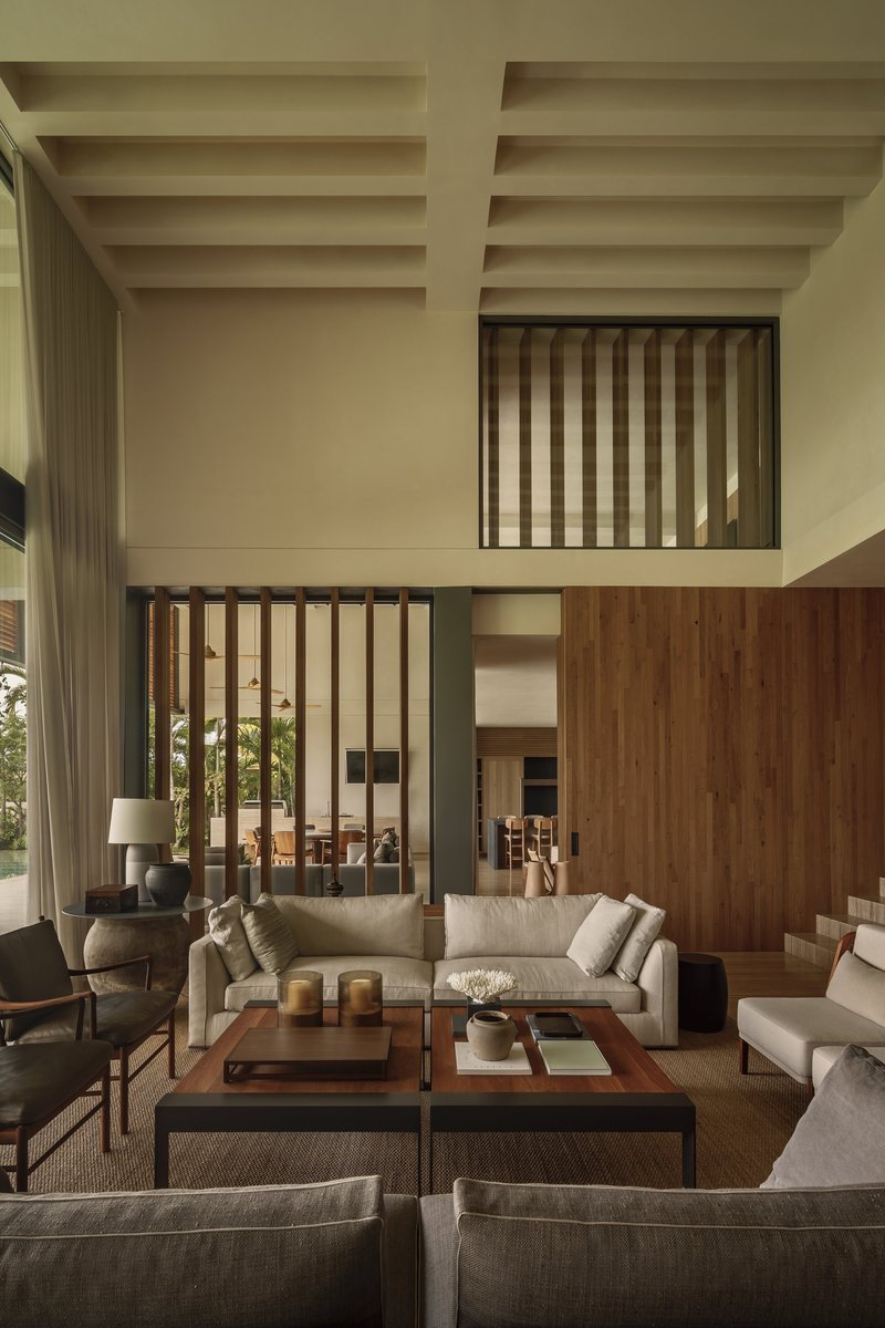 Living room with exposed beam ceiling and timber slat screens framing mezzanine levels above