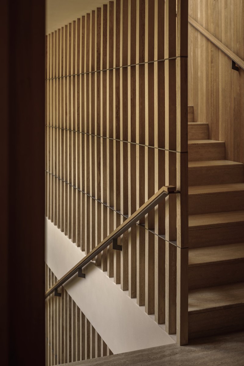 Timber staircase with vertical slat balustrade and bronze handrail alongside ascending steps