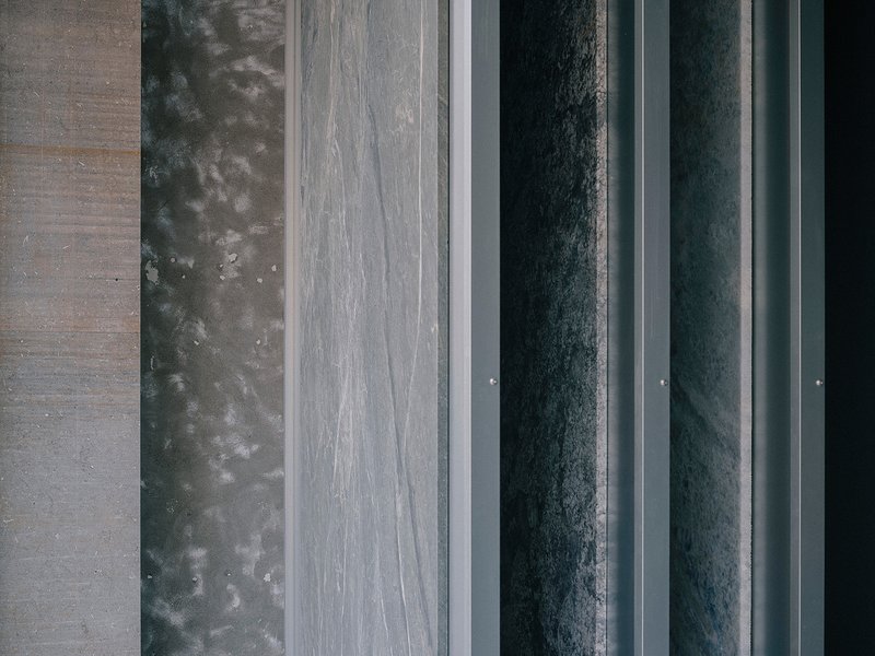 Overhead view of parallel material bands including concrete, dark metal panels and stone pavers