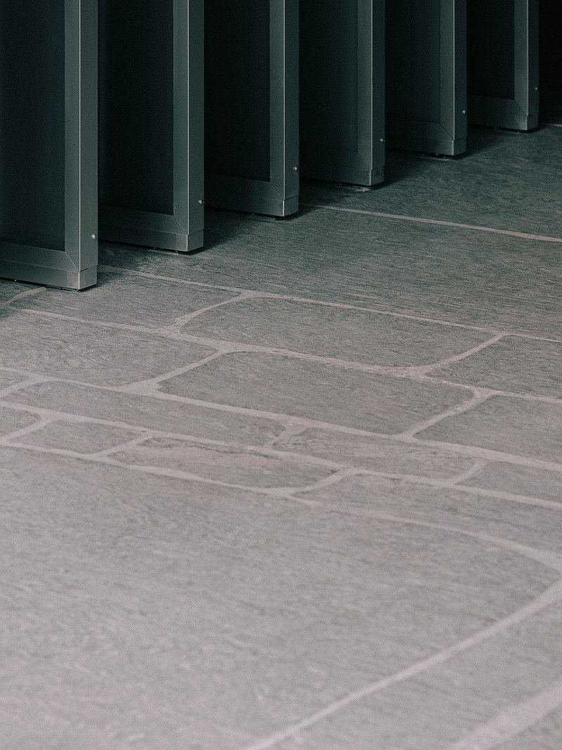Stone tile floor meeting base of dark metal column framework in low light