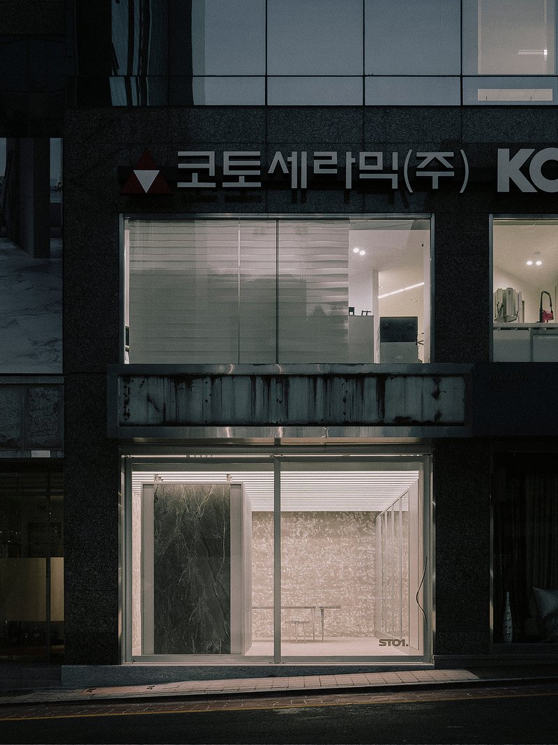 Illuminated storefront with horizontal louvered glass windows in a dark facade at dusk