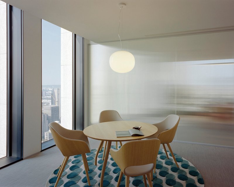 Meeting room with round table and floor-to-ceiling windows overlooking the cityscape