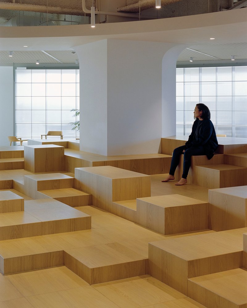 Visitor seated on staggered timber benches beneath an arched opening