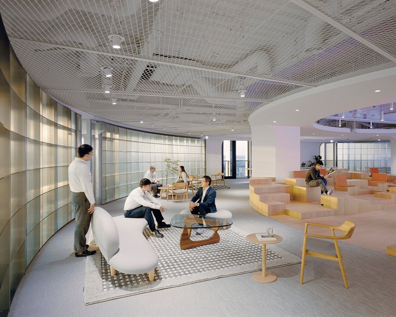 Open office lounge with mesh ceiling and stepped seating platform in use