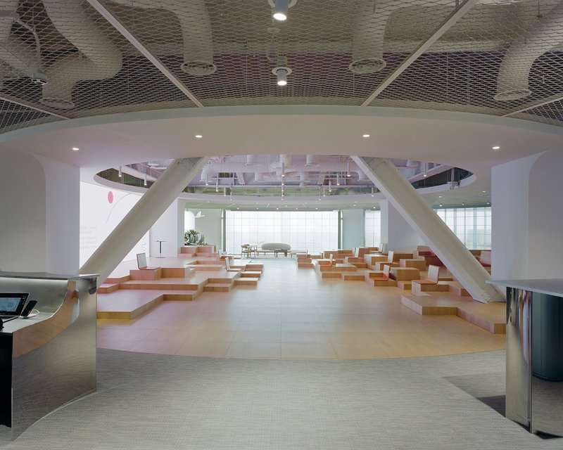 Arched portal framing tiered seating area with diagonal structural beams and metal mesh ceiling