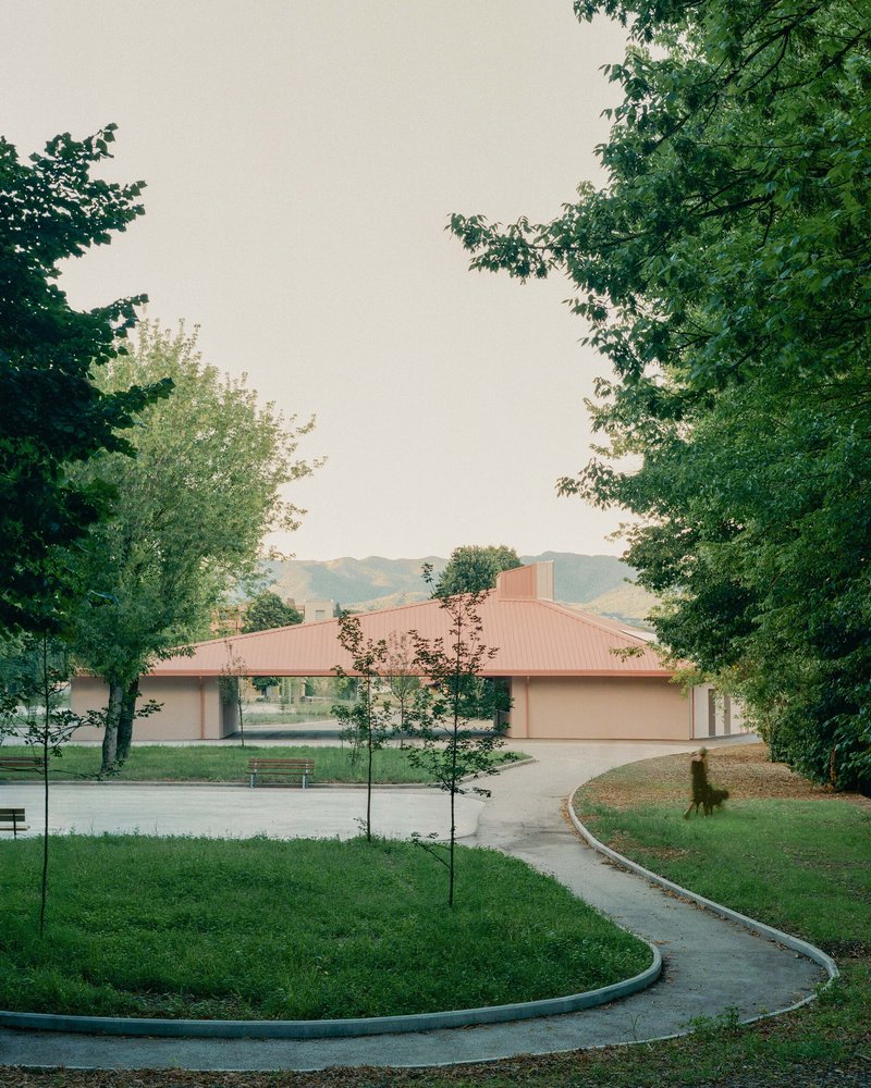 Entry approach with curved concrete pathway and planted beds leading to the hip-roofed pavilion